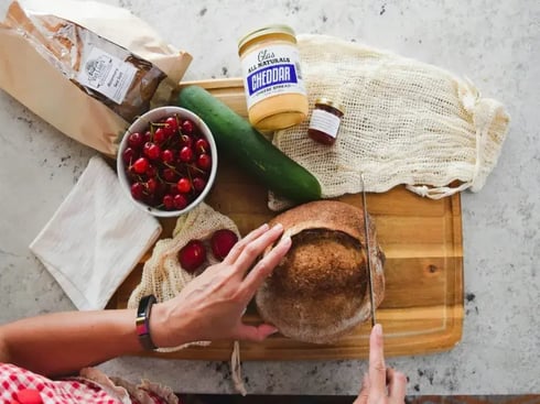 Woman slicing bread with groceries on the table
