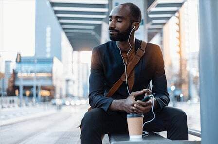 Young businessman with coffee to go listening music